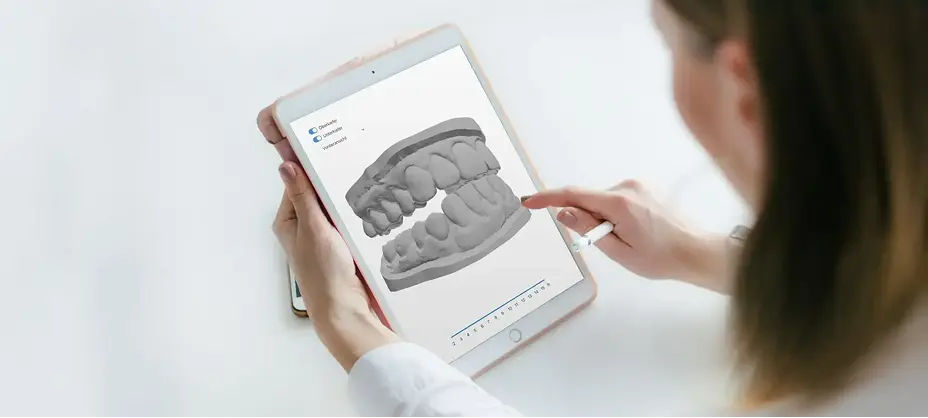 Person interagiert auf einem Tablet mit einem 3D-Modell eines Gebisses.